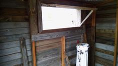 the inside of a wooden cabin with a window and suitcase in it's corner