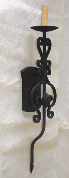 a wall mounted candle holder on the side of a white curtain with a wooden stick sticking out of it