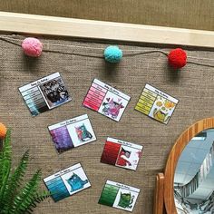 several cards are placed on a table next to a potted plant and mirror with pom - poms