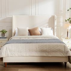 a bed with white sheets and pillows in a room