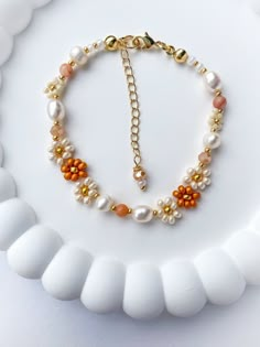 a white plate topped with a gold and pearl necklace on it's side,