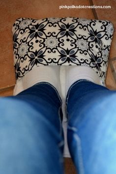 the bottom view of someone's feet wearing blue jeans and white socks with black flowers on them