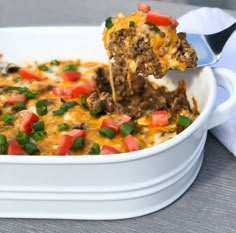 a casserole dish with meat and vegetables being lifted from the casserole