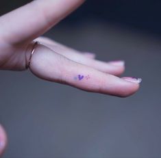 a tiny heart tattoo on the middle finger