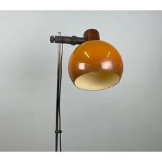 an orange lamp on a black stand against a gray background