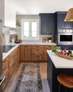 a kitchen with blue cabinets and white counter tops, an area rug on the floor