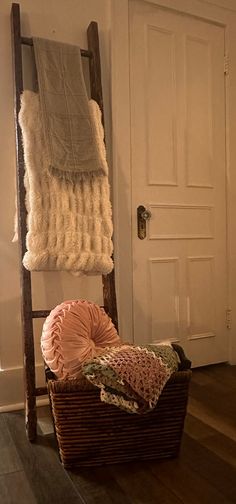 a basket with blankets on top of it next to a door