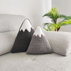 two pillows sitting on top of a couch next to a potted plant