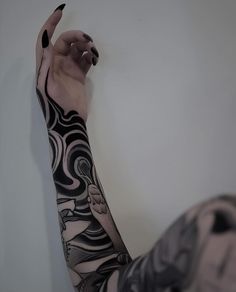 a woman with black and white tattoos on her arm pointing to the side while holding up her hand