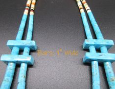 two pieces of turquoise colored beads on a black surface