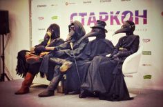 four people wearing masks sitting on a stage