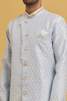 Sky blue sherwani with all over woven floral jaal pattern. Comes with dhoti pant.
Components: 2
Pattern: Woven
Type Of Work: Floral Jaal
Neckline: Mandarin Collar
Sleeve Type: Full
Fabric: Sherwani: Banarasi Zari Jacquard, Dhoti Pant: Silk Dupion
Color: Sky Blue
Other Details: 
Closure: Sherwani: Button
Note: Pocket square worn by model is not for sale
Occasion: Mehendi and Puja,Sangeet - Aza Fashions Sky Blue Sherwani, Dhoti Pants For Men, Blue Sherwani, Dhoti Pants, Jacquard Weave, Mandarin Collar, Pocket Square, Aza Fashion, Sleeve Type