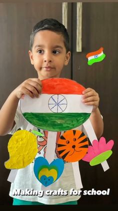 a young boy holding up a paper plate with the flag of india painted on it