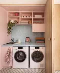 a washer and dryer in a small room with pink cabinets on the wall