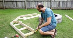 a man is working on some kind of wooden structure in the yard with his tools