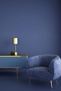 a blue chair sitting next to a table with a lamp on it