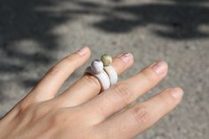 a woman's hand with two rings on it, one is white and the other is green