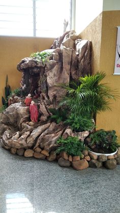 there is a fake waterfall in the center of this room with rocks and plants around it