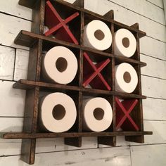 a wooden rack with several rolls of toilet paper in it and two red crosses on the top