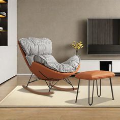 a living room with a chair, ottoman and television on the wall in front of it