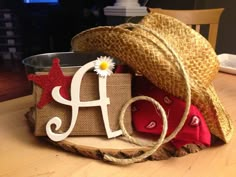 a straw hat sitting on top of a wooden table next to a paper bag with the letter a