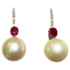 A Pair of Ruby, Champagne Colour South Sea Pearl and Diamond Earrings in 18k White Gold. It is a simple drop design with the pearls hanging underneath the ruby, it is then connected to the shepherd hook. Diamonds are set on the front of the shepherd hook. The pearls are round in shape and measuring 11 mm - 11.5 mm. The pearls are champagne colour with green overtone. The pearls are of good lustre with minor surface blemishes. Total ruby weight is 0.97 ct Total diamond weight is 0.138 ct The colour of the diamonds are approximately E/F with VS clarity Fine Jewelry Pearl Earrings With Pear-shaped Gemstone, Luxury Elegant Red Pearl Earrings, Luxury Pearl Drop Ruby Jewelry, Luxury Red Pearl Earrings, Elegant Style, Luxury Gold-tone Pearl Drop Earrings, Color Champagne, Pearl And Diamond Earrings, South Seas, Sea Pearls