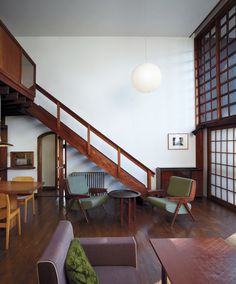 a living room filled with furniture next to a wooden stair case under a light fixture