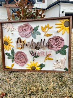 a sign with flowers on it sitting in the grass