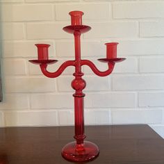 a red candelabra sitting on top of a table next to a brick wall