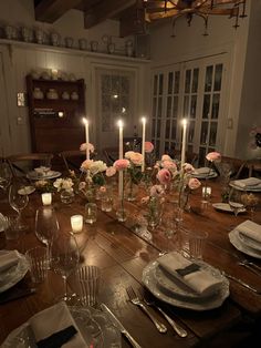 a wooden table topped with lots of plates and glasses filled with flowers on top of it