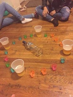 two people sitting on the floor with cups in front of them and one person laying on the floor