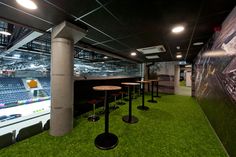 an empty sports bar with grass on the floor and stools in front of it