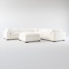 a white couch and ottoman in front of a gray wall with no one sitting on it