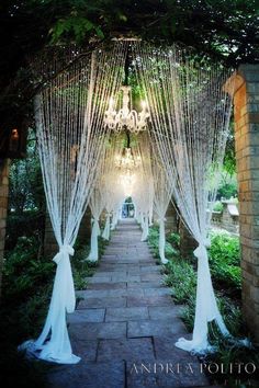 an archway decorated with white curtains and lights