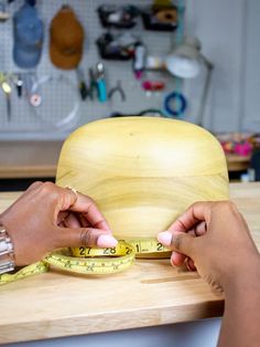 two hands measuring the width of a wooden hat