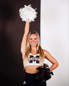 a beautiful young woman holding a cheerleader pom in her hand