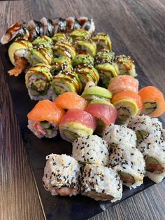 sushi and rolls are arranged on a black plate