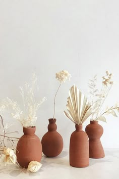 three clay vases with flowers in them