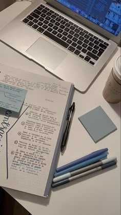 a laptop computer sitting on top of a white desk next to a cup of coffee