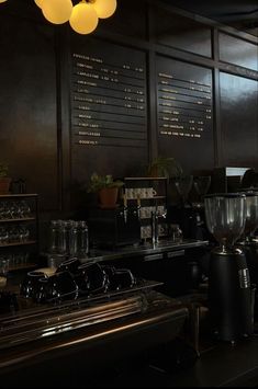 the coffee shop has many cups on the counter and there are lights hanging from the ceiling