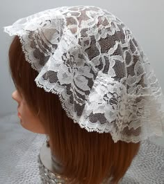 a mannequin head wearing a white lace bonnet