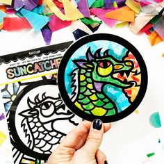 a person holding up a paper cut out of a dragon and rainbow confetti