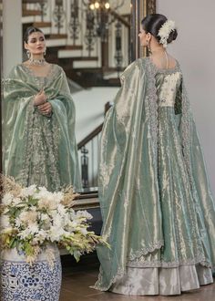 two women in green dresses standing next to each other and looking at their own reflection