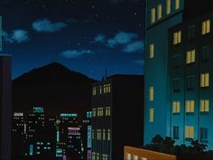 the city skyline is lit up at night, with buildings and mountains in the background