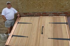 a man standing next to a wooden table with scissors on it and another person behind him