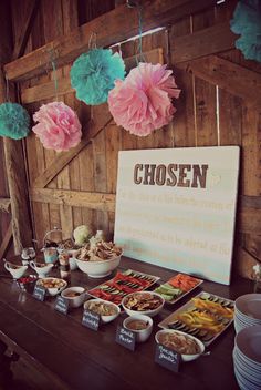 a wooden table topped with plates and bowls filled with food next to a sign that says chosen