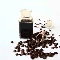 coffee beans spilled out of a glass jar next to a wooden spoon