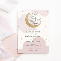 a pink and gold baby shower with the moon on it, next to some white sheets