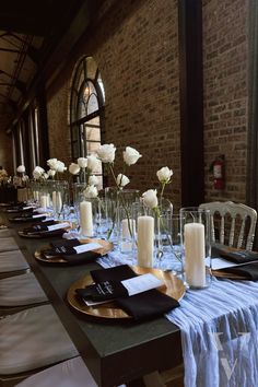 a long table is set with white flowers and place settings for the guests to sit down