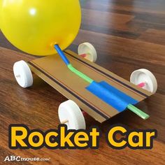 a rocket car made out of cardboard on a wooden floor with an air ball attached to it